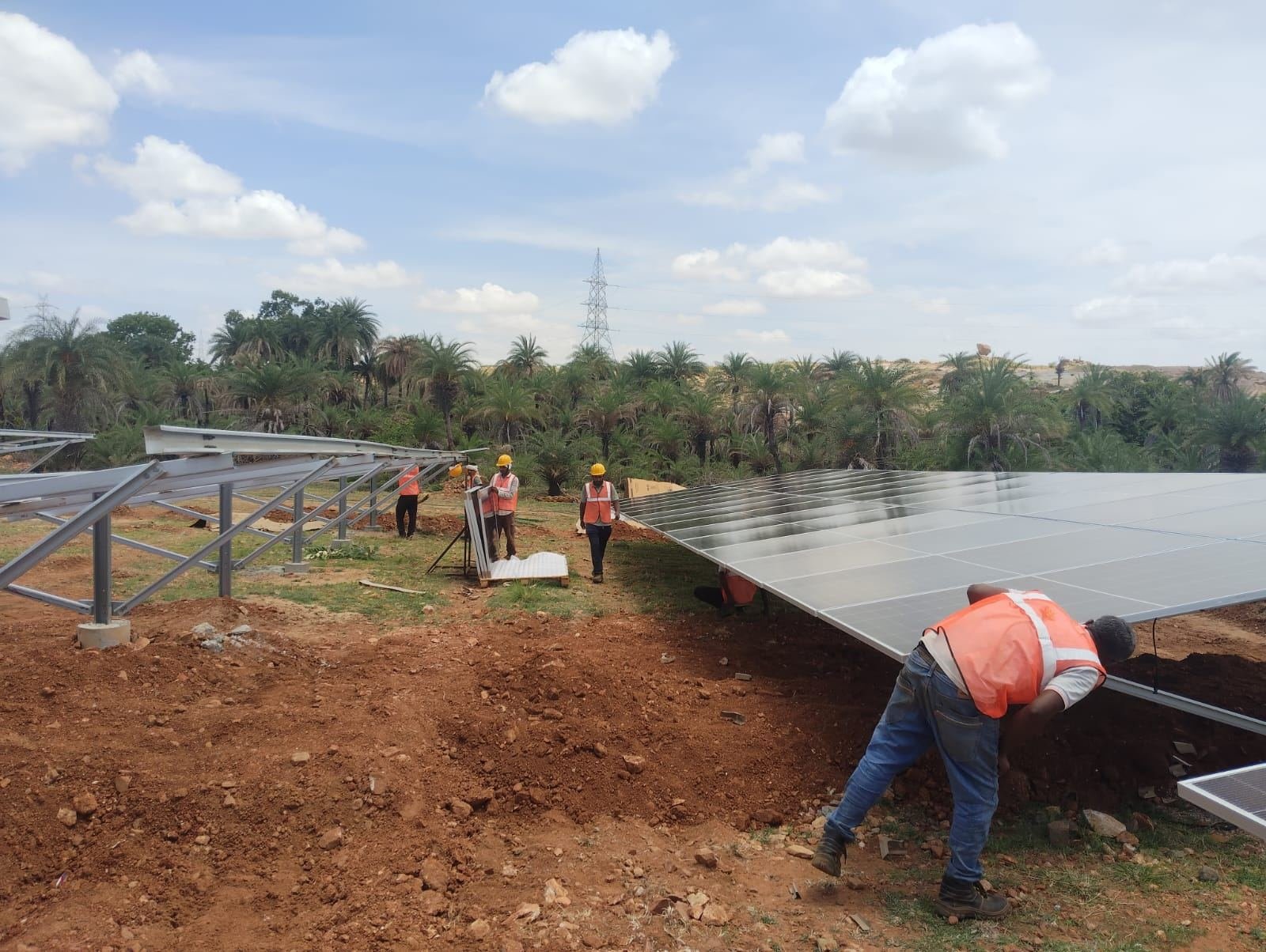 Workers installing solar panels at the Ramgir JSW solar farm